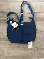 Full view of navy Baggallini Everywhere Bagg with strap and tags