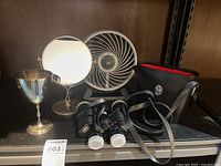 Group shot of all items: binoculars, case, fan, mirror, cup