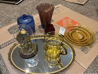 All items grouped: blue cookie jar, amber jug, amber platter, red vase, purple vase, dome clock, mirrored tray