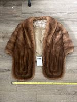 Full view of fur stole front open on floor with tape measure