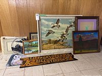 Group of nine artwork and décor pieces displayed against wood panel wall