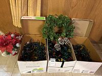 Overall lot showing three boxes of lights, wreath, and poinsettia arrangement