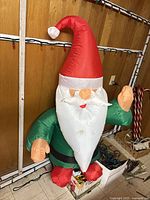Inflatable Santa figure standing beside wall with string lights