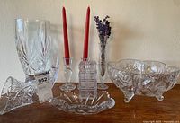 Group shot of all cut glass items including two vases, bowl, dish, candlesticks and candles