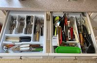 Two open drawers showing flatware and utensils