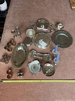 Group shot of all silver-plated and pewter pieces on carpet with measuring tape for scale