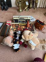 Lot overview showing radio, Clue game, cribbage board, playing cards, binocular case, plush toys