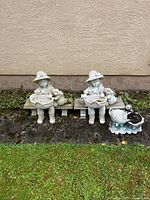 Front view of both girl statues on benches with duck planter