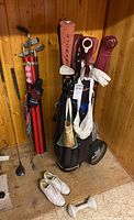 Full view of golf bag on pull cart with clubs, shoes and red practice shafts