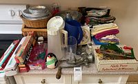 Countertop view showing majority of items including pitchers, pie plates, baskets, wraps, timer, grinder and linens