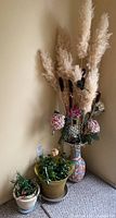 Floor grouping showing two potted plants and large vase with dried/ artificial arrangement