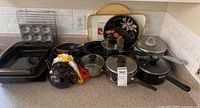 Overview of assorted cookware, bakeware, trays, teapot and utensils on countertop
