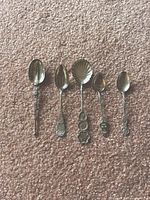 Five sterling silver spoons laid out on carpet