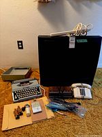 Group shot of all items including TV, typewriter, radio, telephone, cash box, office supplies and cables