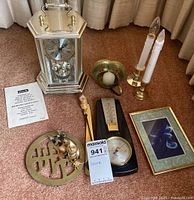 Group shot of all items including clock, weather station, candlesticks, bowl, frame, plaque and figurines