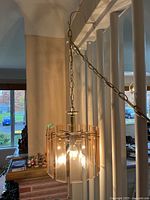 Overall view of hanging brass fixture with chain and lit bulbs