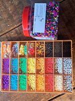 Open storage box showing 24 colour-sorted bead compartments beside IKEA jar