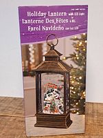 Front of boxed holiday lantern showing product image and branding