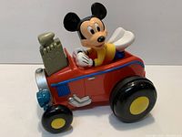 Side view of Mickey Mouse plastic pull-back car showing figure, body, wheels, engine detail