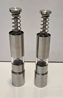 Front view of both stainless steel pump-action grinders showing full design and clear acrylic window