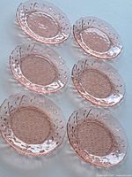 Six pink embossed glass plates arranged to show design and quantity