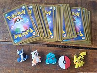 Stack of Pokémon card backs with five shoe charms laid out