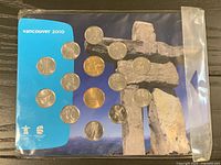 Front of sealed coin set showing 14 coins on inukshuk background card
