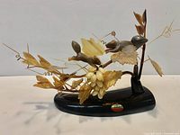 Overall view of resin squirrel and grapevine sculpture on black base with maker sticker visible