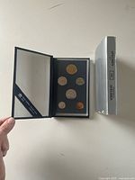 Set open showing six coins in holder and outer silver sleeve