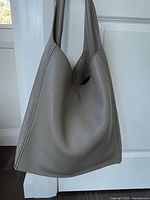 Front view of gray pebbled-leather hobo tote hanging from a door knob