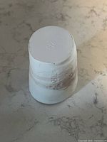 Underside of unglazed porcelain cup showing maker’s mark and matte finish