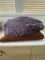 Both fabric pieces folded; purple on top, brown curly-pile below