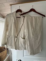 Full view of blazer and trousers hanging, showing pinstripe pattern and overall condition