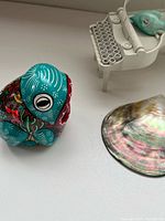 Top view of ceramic frog, metal typewriter figurine with bird, and abalone shell