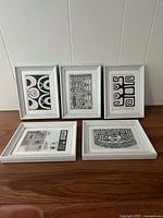 group shot of five framed items showing prints and empty frame