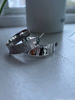 Pair of hammered silver half-hoop earrings showing overall design and finish