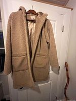 Full view of beige teddy coat hanging on door