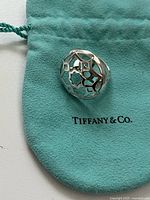 Ring displayed on Tiffany pouch showing top floral cutout design