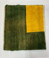Full view of rug showing green field and yellow block