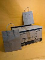 Closed carton labelled Comates EM-8450 with two sample brown kraft bags displayed