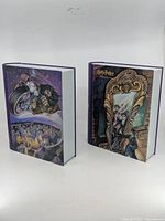 Both tin book boxes standing closed showing different cover art