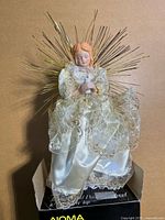 Porcelain angel tree topper out of box showing gown, halo and light cord