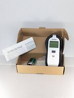 Stud finder in open carton with 9-volt battery and leaflet