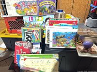 Assorted board games and puzzles stacked on bin