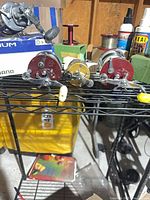 Four Penn conventional reels lined up on wire rack with two extra spools visible behind