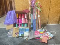 Full lot showing wrapping paper rolls, curling ribbon box, cellophane rolls, gift bags and loose ribbon