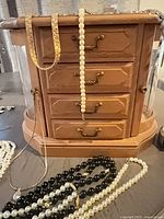 Wooden jewelry box with multiple necklaces draped