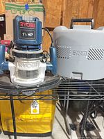 Front view of Ryobi 1.5 HP router beside gray case