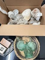Box of assorted seashells and coral, basket with green glass bottles, soap dish and air-freshener refills