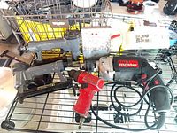 Lot overview showing drill, air grinder, two staplers, drill bit case, basket